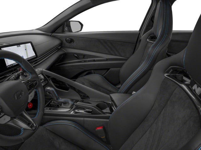 Interior view of dark gray car seats with blue stitching and a modern dashboard with a screen.