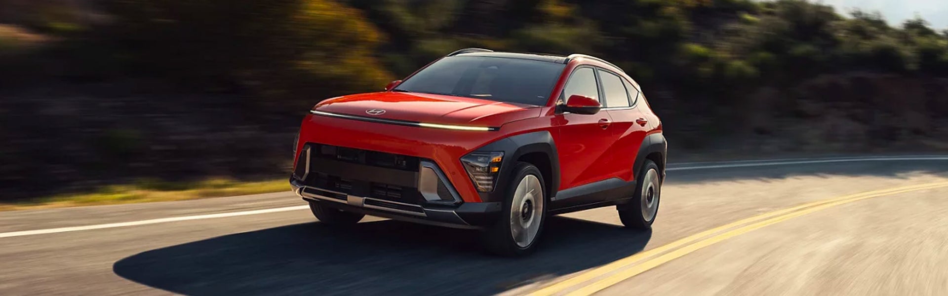 Front view of a red SUV with bright LED lights, driving on a highway with motion blur.