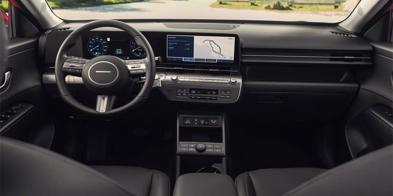 Interior view of a modern car dashboard with a steering wheel, digital gauges, a large touchscreen, and climate controls.