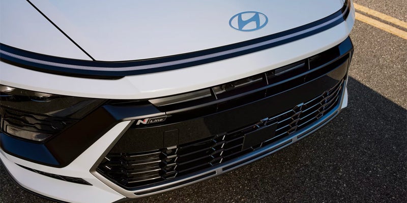 Front view of a white Hyundai, showing the logo, horizontal lighting, grille, and "N" badging on the bumper.