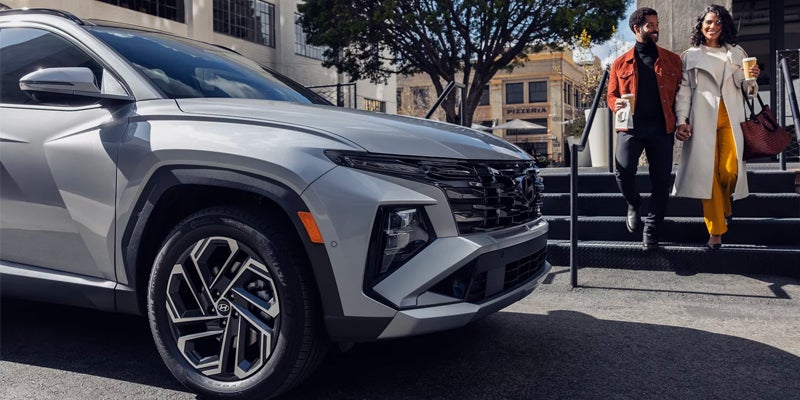 Silver Hyundai SUV parked as a couple walks down steps in the background.