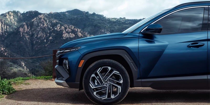 Front quarter view of a dark blue SUV with mountains in the background.