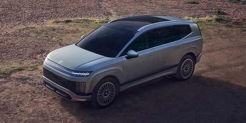 Light grey Hyundai SEVEN electric SUV concept car with a black roof, parked on a dirt road.