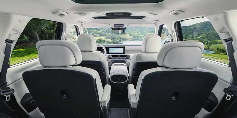 View from the back of a luxury SUV, showing two back seats, two middle seats and dashboard through the windshield.