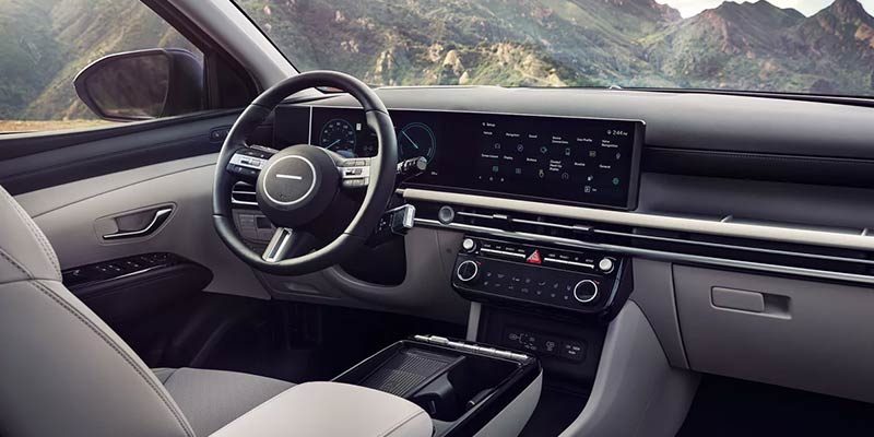 The interior of a modern car with a digital dashboard, large infotainment screen, and light gray and black accents.